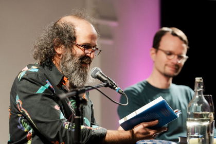 © Michael Kohls Tomer Gardi beim Lesen, neben ihm Gastgeber Sebastian Schirrmeister